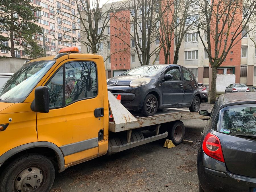 Enlèvement d'une Citroën C1 sur le parking d'un grand ensemble, véhicule déjà sur la dépanneuse